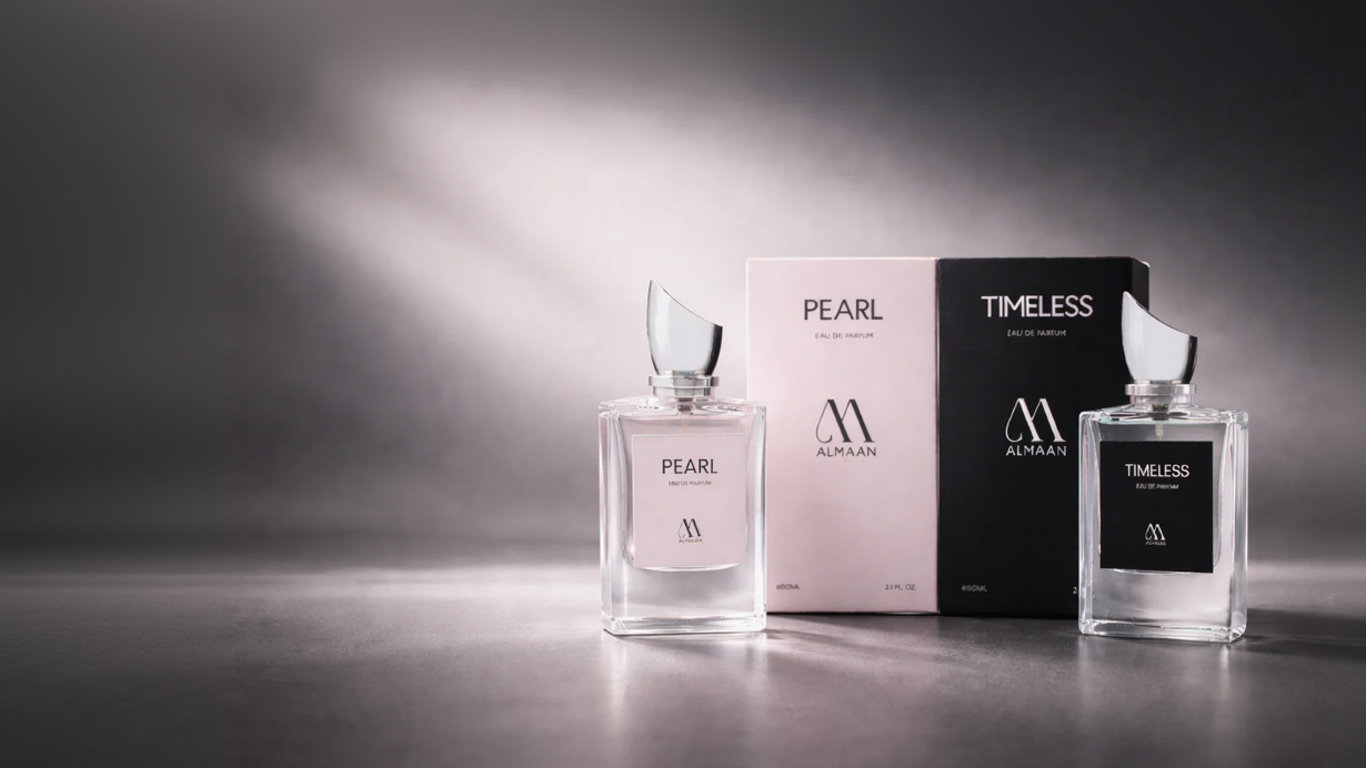 Two Almaan perfume bottles, 'Pearl' and 'Timeless', with their packaging on a reflective surface.